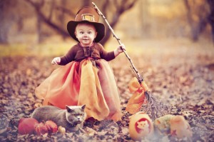 A child wearing a Halloween outfit with a cat outside